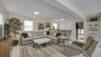 A spacious living room with a sectional sofa, a coffee table, and a large plant.