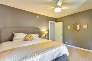 A bedroom with a bed, a ceiling fan, a door, and a wall-mounted mirror. - Dog-friendly Watertown Vacation Rental w/ Deck (Watertown)