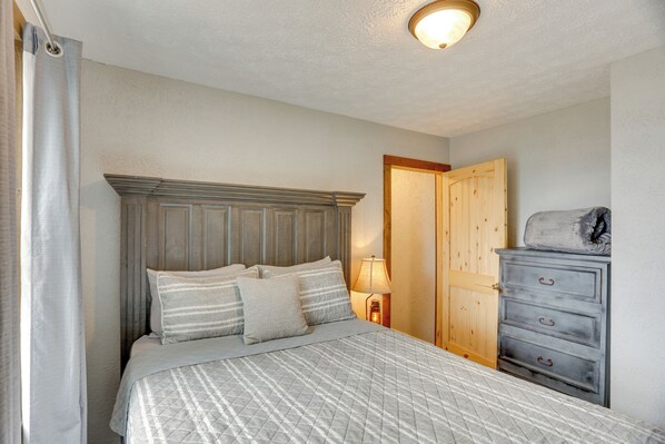 A bedroom with a bed, a nightstand, a dresser, and a door.