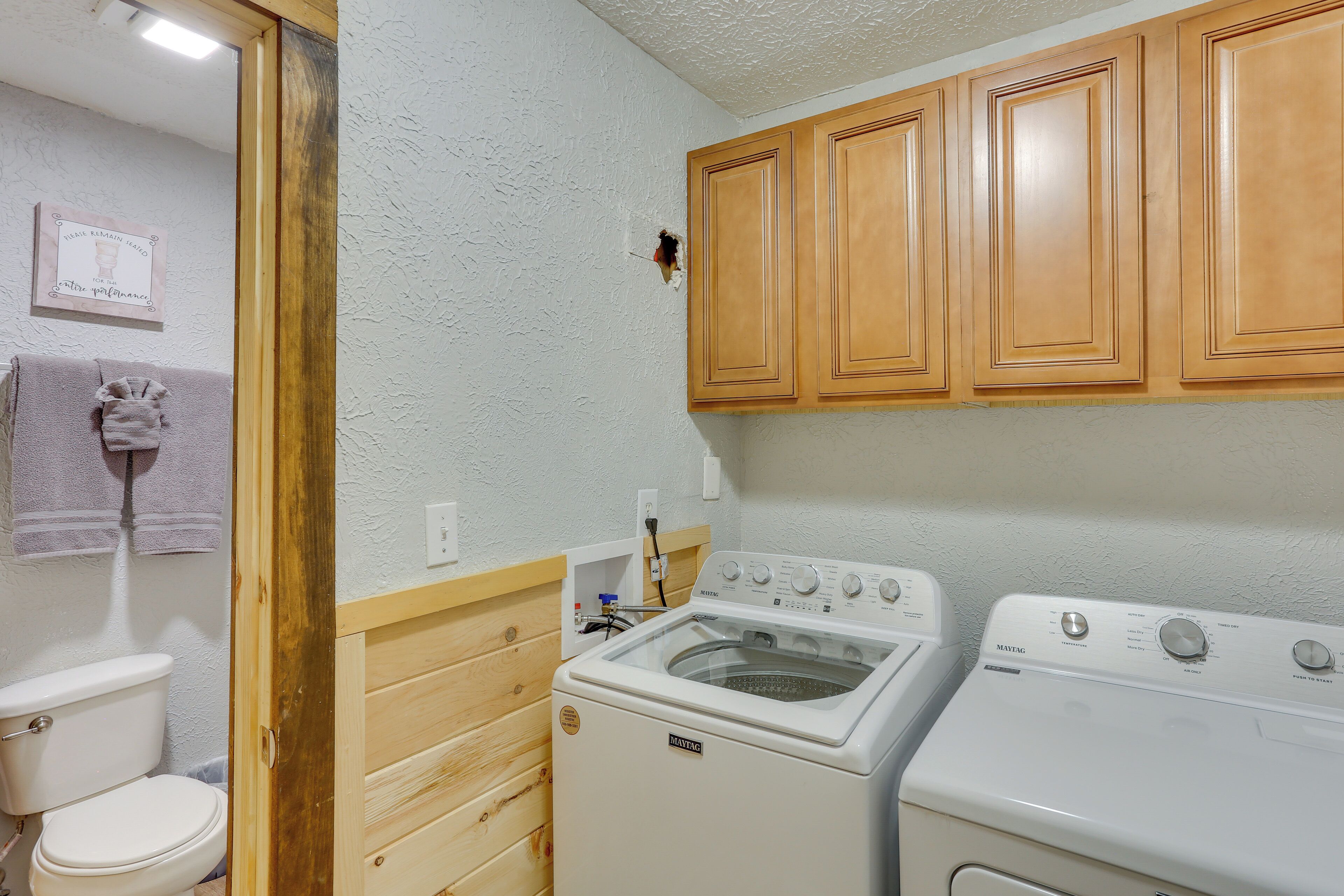 A laundry room with wooden cabinets, a washing machine, and a dryer.