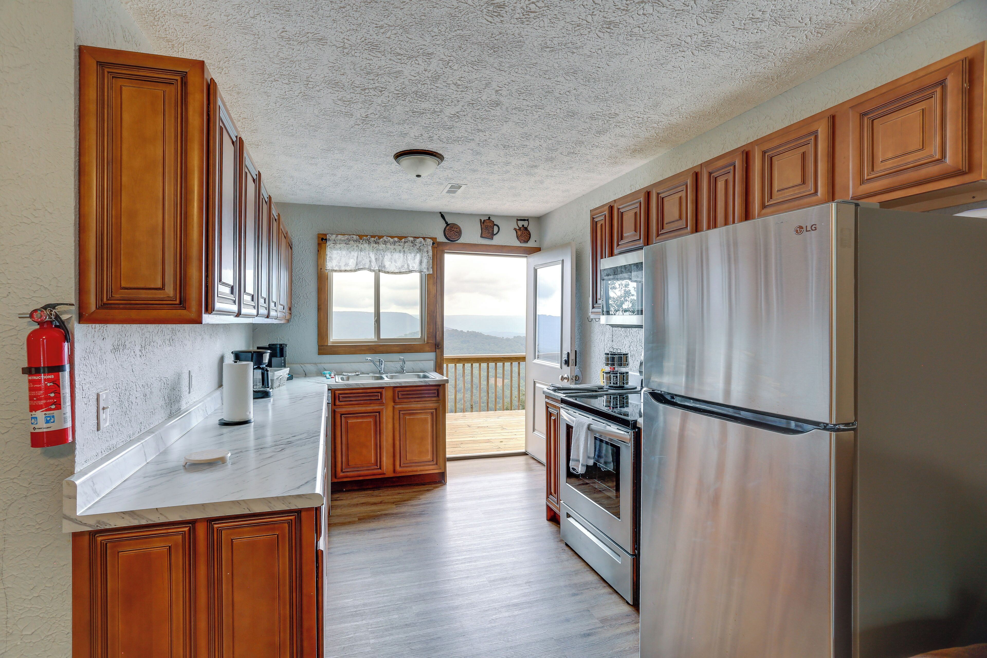 A kitchen with wooden cabinets, a stainless steel refrigerator, and a large window overlooking a scenic view.