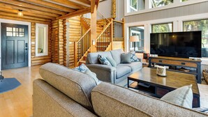 A log cabin interior with a staircase, a large flat-screen TV, and a cozy seating area. - Gorgeous Long Lake Home w/ Dock, Kayak, SUP & More (Lacey)