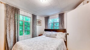 A bedroom with a large bed, two windows with curtains, a wooden headboard, and a framed picture on the wall. - Salisbury Cottage ~ 7 Mi to High Rock Lake! (Salisbury)