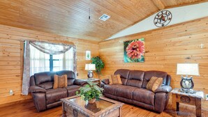 L’intérieur d’un chalet confortable, avec deux canapés en cuir, une table basse en bois et un emblème de l’État du Texas accroché au mur.