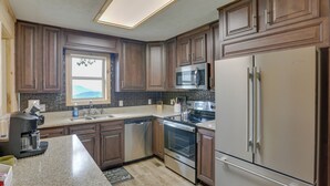 Une cuisine avec des meubles en bois foncé, des appareils en acier inoxydable, un four à micro-ondes encastré et une grande fenêtre.