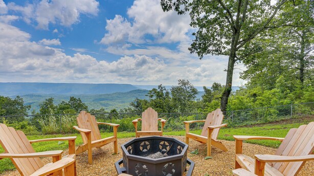 Un foyer circulaire en bois, entouré de chaises Adirondack, installé sur une surface de gravier et offrant une vue panoramique sur les montagnes et les arbres en arrière-plan.