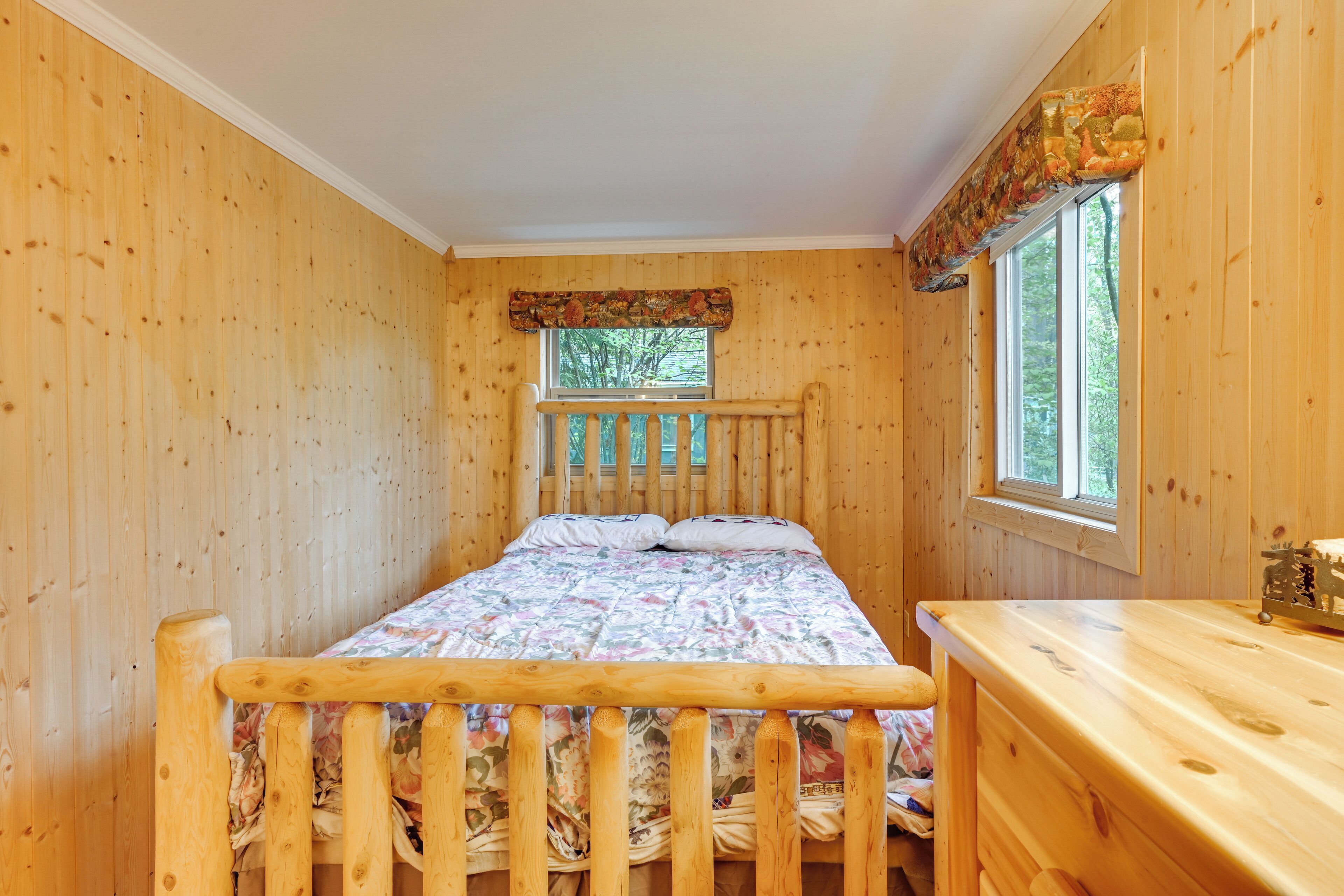 Une pièce en bois avec un lit, une fenêtre et une commode en bois.
