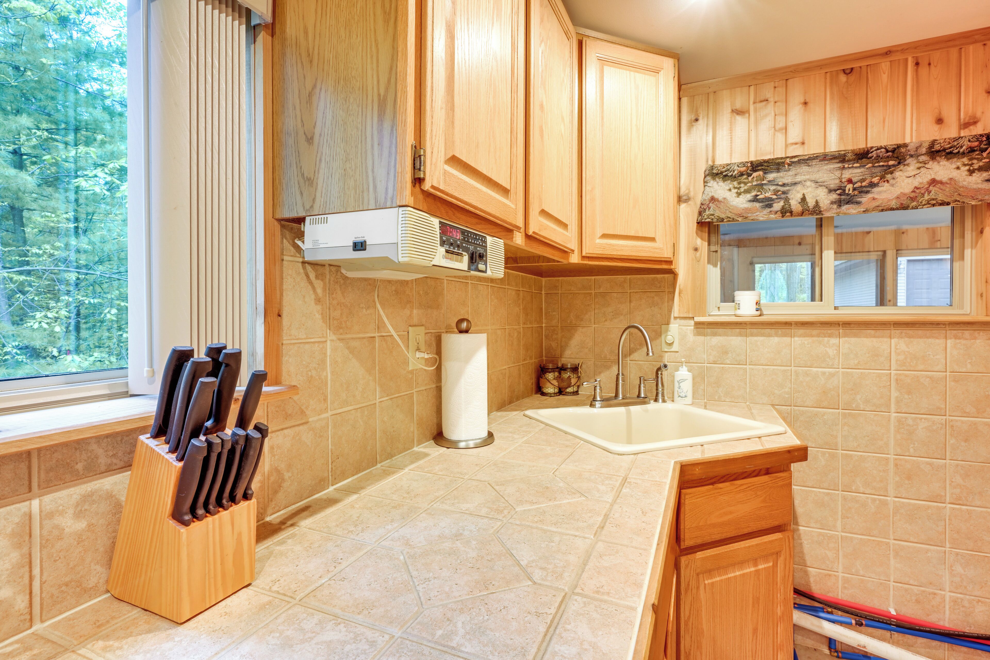 A kitchen with wooden cabinets, a window, a sink, and a knife block.