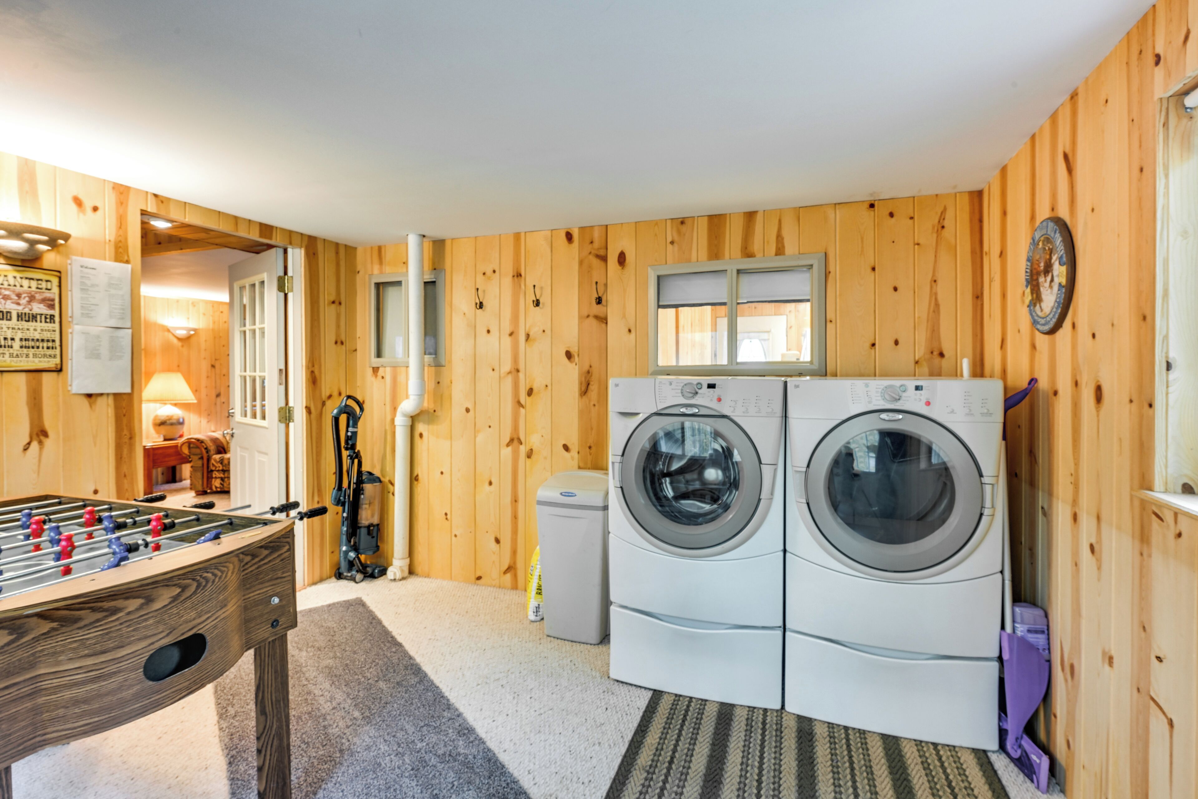 A laundry room with two washing machines, a foosball table, and wooden walls.