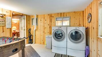 A laundry room with two washing machines, a foosball table, and wooden walls.