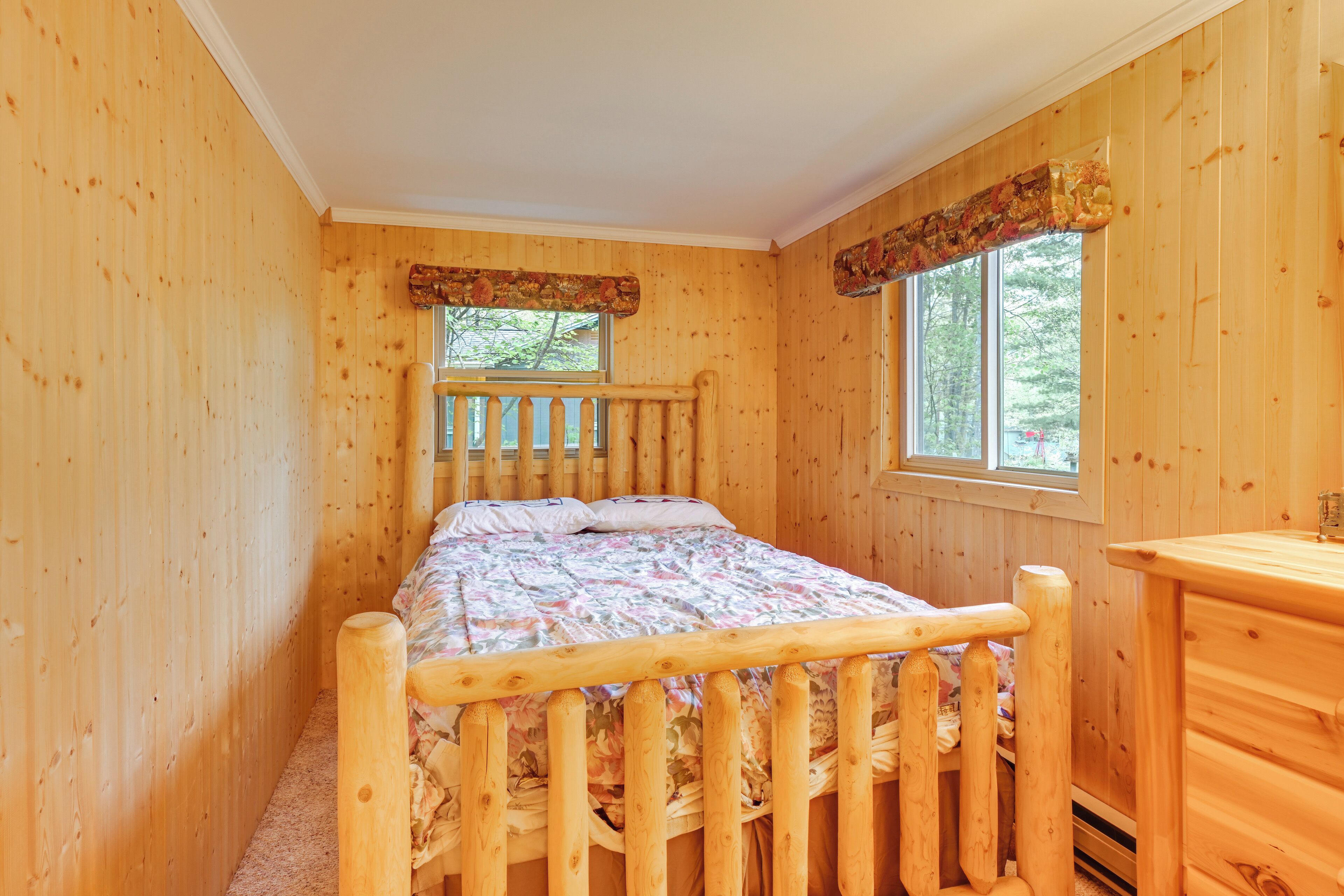 A wooden room with a bed, a window, and a wooden dresser.