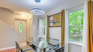 Ein moderner Essbereich mit Glastisch und Stühlen, einer Treppe und Blick auf Grünflächen.
