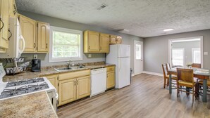 Une cuisine dotée de meubles en bois, d’un lave-vaisselle, d’un réfrigérateur et d’un coin repas avec des chaises et une table.
