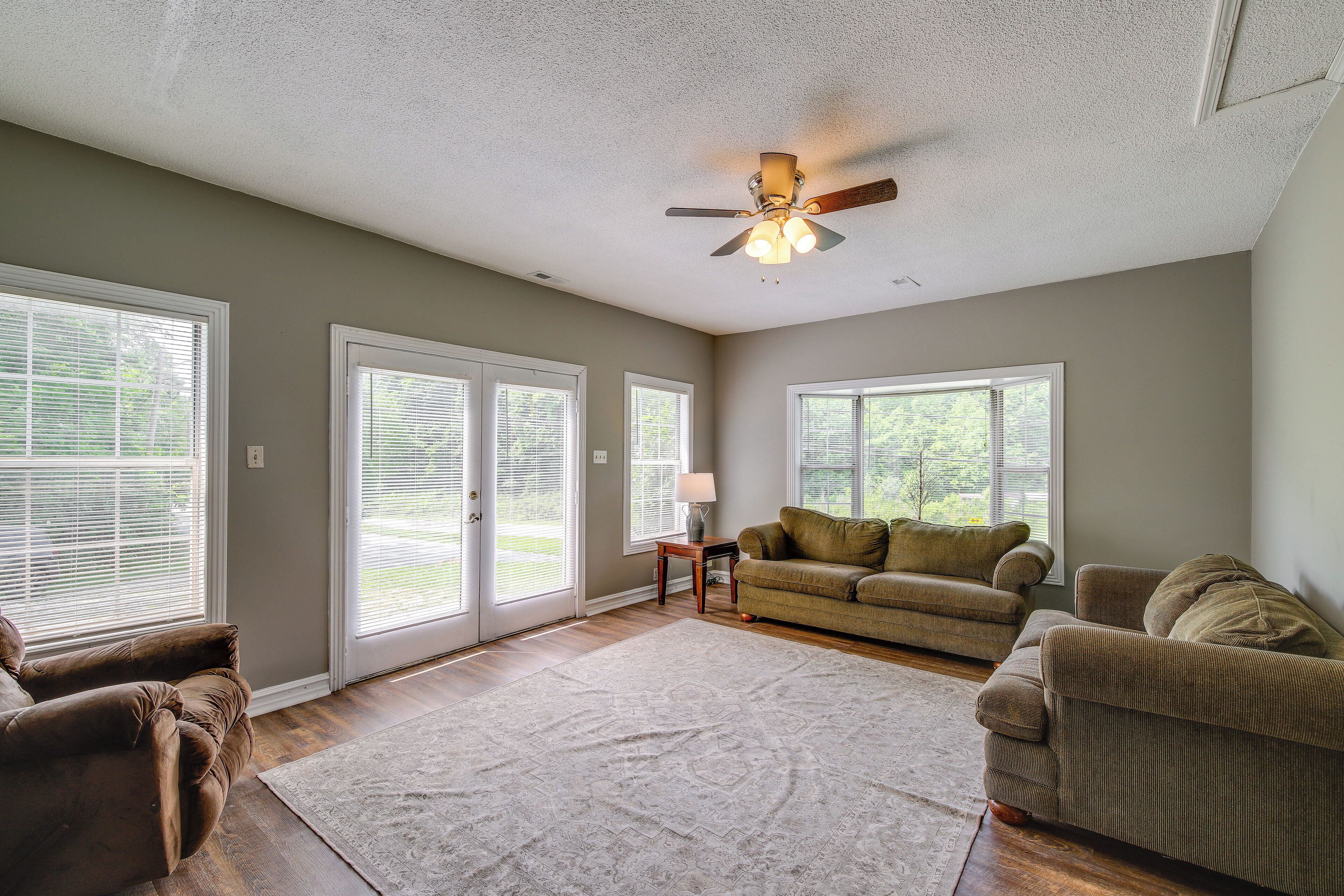 A spacious living room with a large window, a ceiling fan, and a sofa.