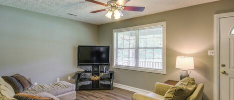 A living room with two sofas, a TV, and a ceiling fan.
