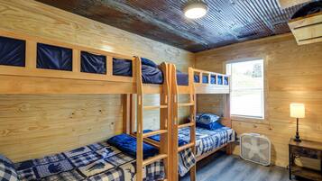 Habitación con literas, ventana, ventilador y mesita de noche.