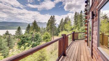 A wooden deck with a view of a forest and mountains.
