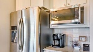 A stainless steel refrigerator and microwave in a kitchen with white cabinets and a coffee maker on the counter. - Russellville Home Near Hiking + Lake Access! (Russellville)
