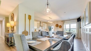 A dining area with a long wooden table, multiple chairs, and a hanging light fixture. - Russellville Home Near Hiking + Lake Access! (Russellville)