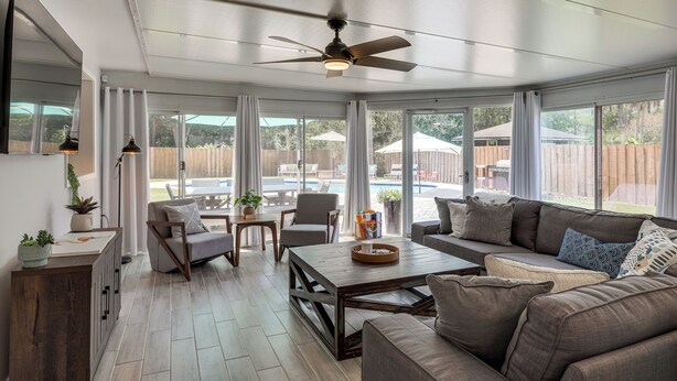 A spacious living area with a ceiling fan, large windows, a sofa, a coffee table, and a dining table. - Ponte Vedra Beach Vacation Rental w/ Private Pool! (Ponte Vedra Beach)