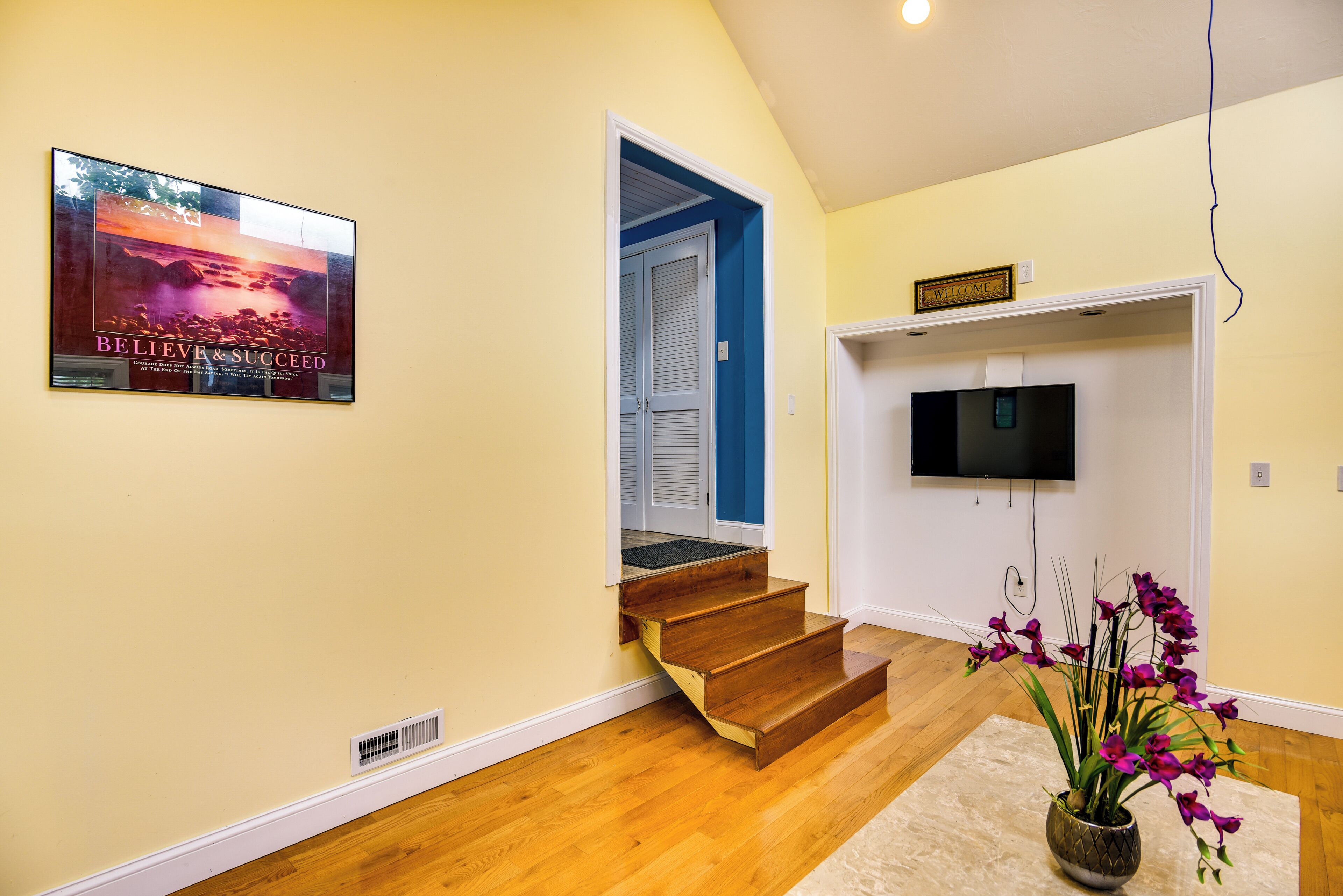 A staircase leading to a room with a television and a welcome sign.