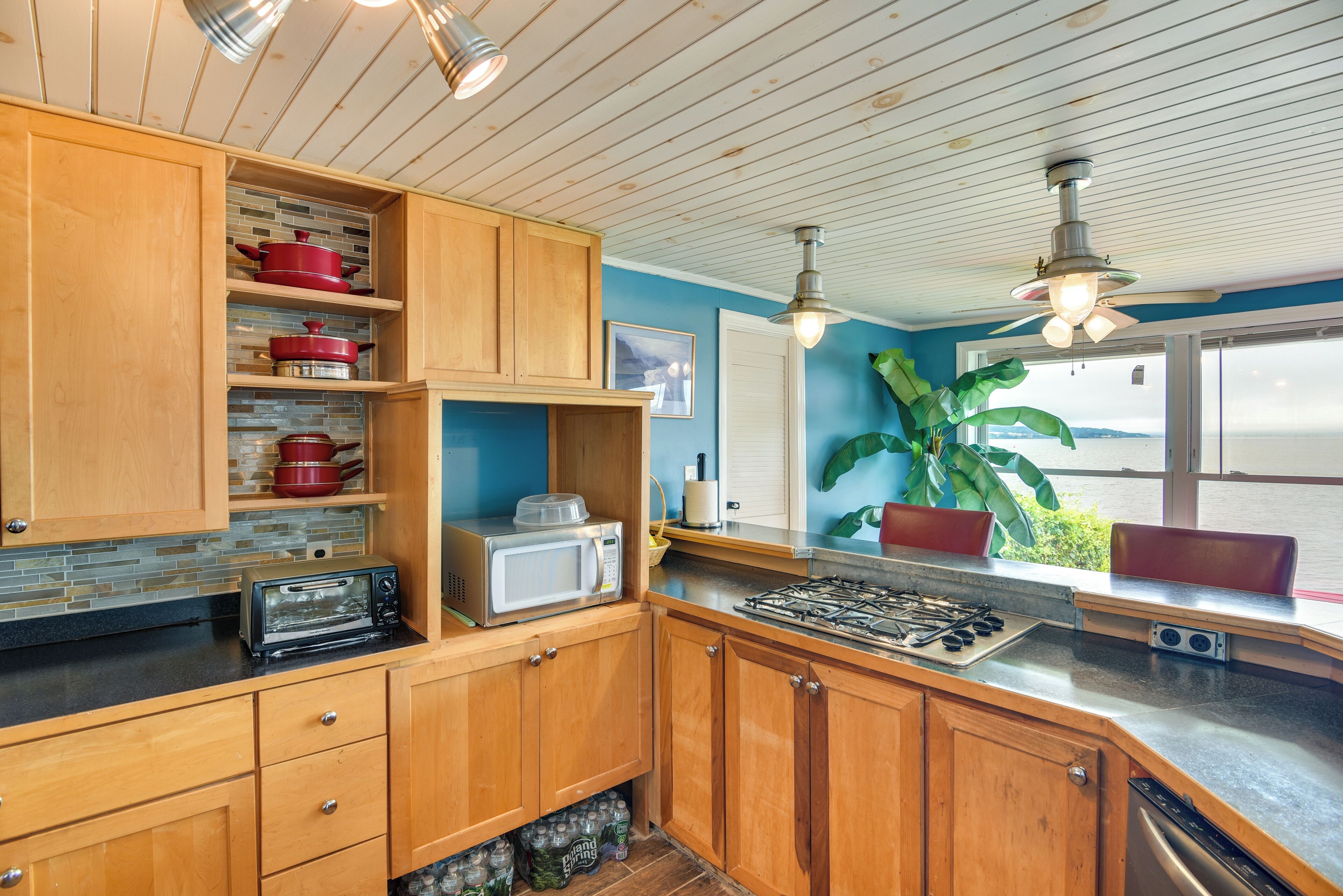 Une cuisine avec des meubles de rangement en bois, un four à micro-ondes, une cuisinière et un lave-vaisselle.