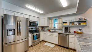 A modern kitchen with stainless steel appliances, white cabinetry, and a marble countertop. - Breezy Englewood Condo w/ Community Pool! (Englewood)