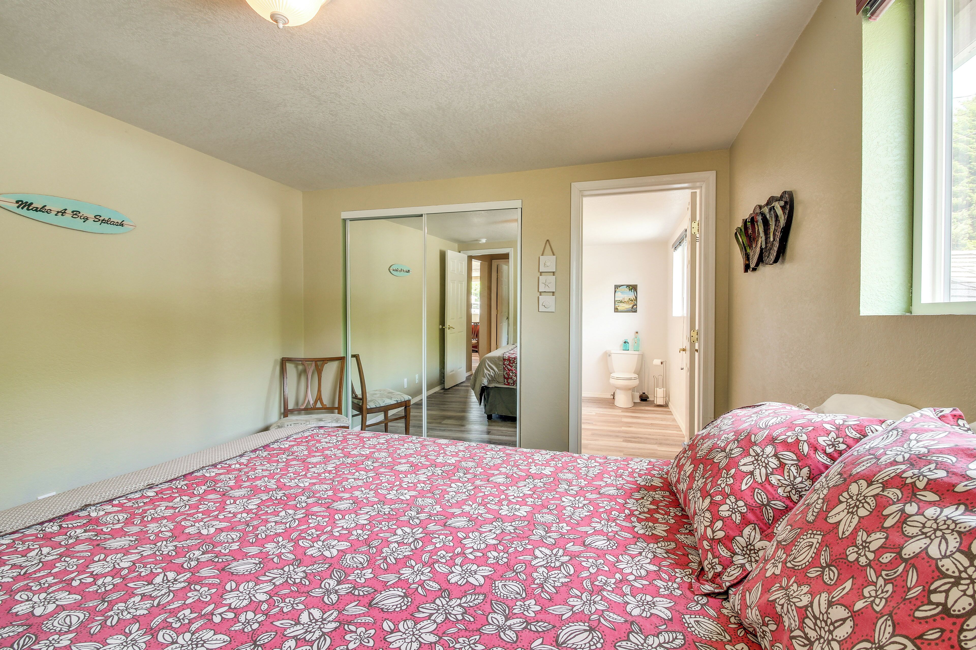 Un dormitorio con cama, espejo y puerta que da a otra habitación.