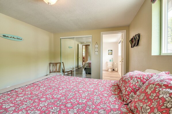 A bedroom with a bed, a mirror, and a door leading to another room. - Winchester Bay Vacation Rental Near Dunes & Atv! (Reedsport)