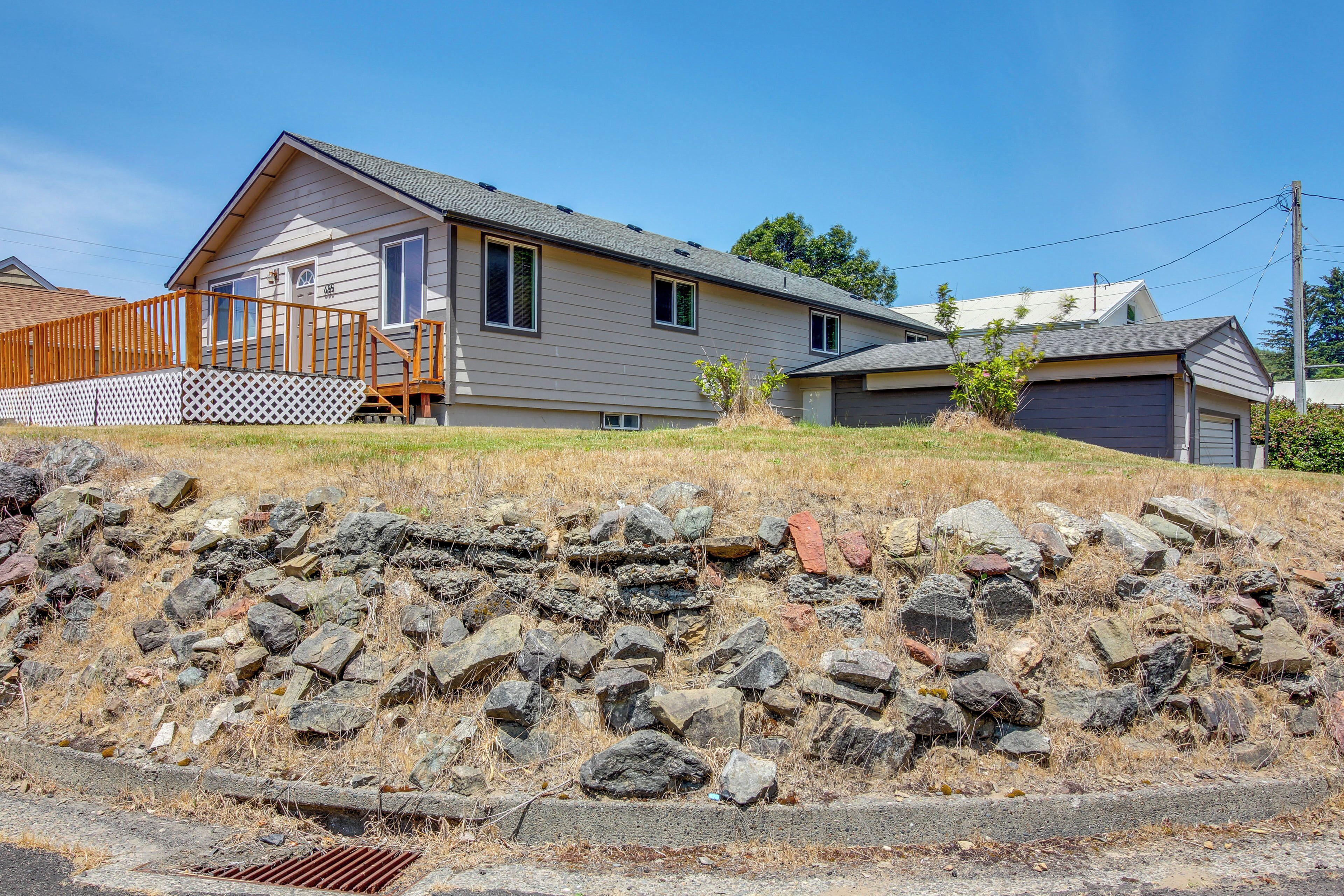 A residential house with a wooden deck, a garage, and a stone retaining wall.