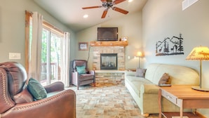 A living room with a fireplace, leather sofas, a wooden coffee table, and a ceiling fan. - Pet-friendly Wisconsin Cabin on Lake w/ Fire Pit! (Townsend)