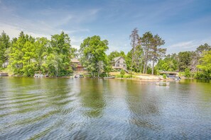 Een vakantiehuis aan het meer met huizen, een aanlegsteiger en een boot.