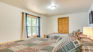 A bedroom with two beds, a wooden door, and a window with curtains. - Pet-friendly Wisconsin Cabin on Lake w/ Fire Pit! (Townsend)