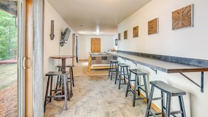 A kitchen with a bar area, stools, and a view of the outdoors. - Pet-friendly Wisconsin Cabin on Lake w/ Fire Pit! (Townsend)