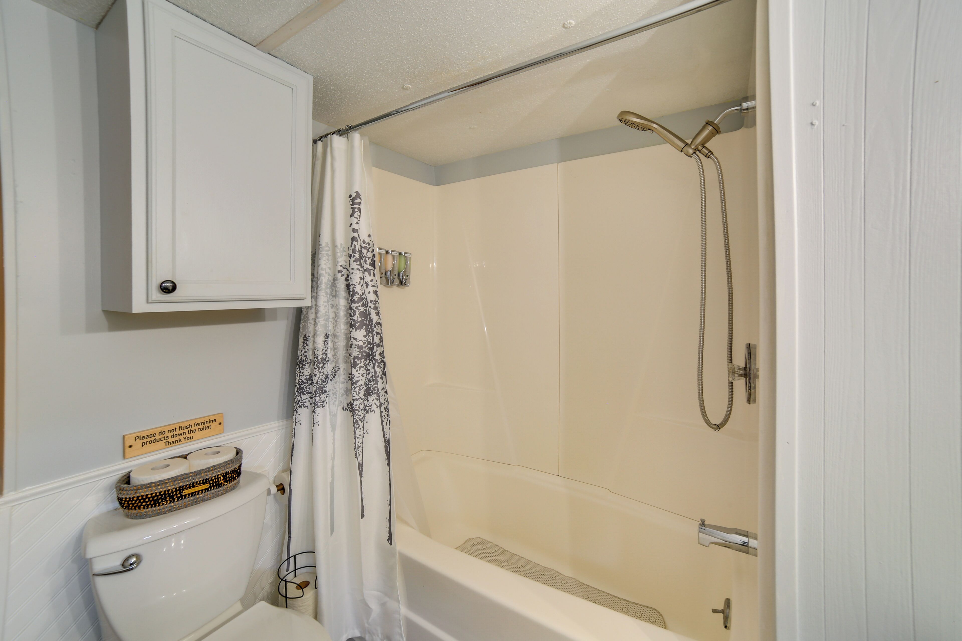 A bathroom with a toilet, a shower, and a cabinet.