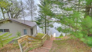 A wooden staircase leading to a cabin labeled "PRIVATE Sunset Bay Cottage" with a view of a lake and surrounding trees. - Lakefront Wisconsin Home w/ Boat Dock & Fire Pit! (Townsend)