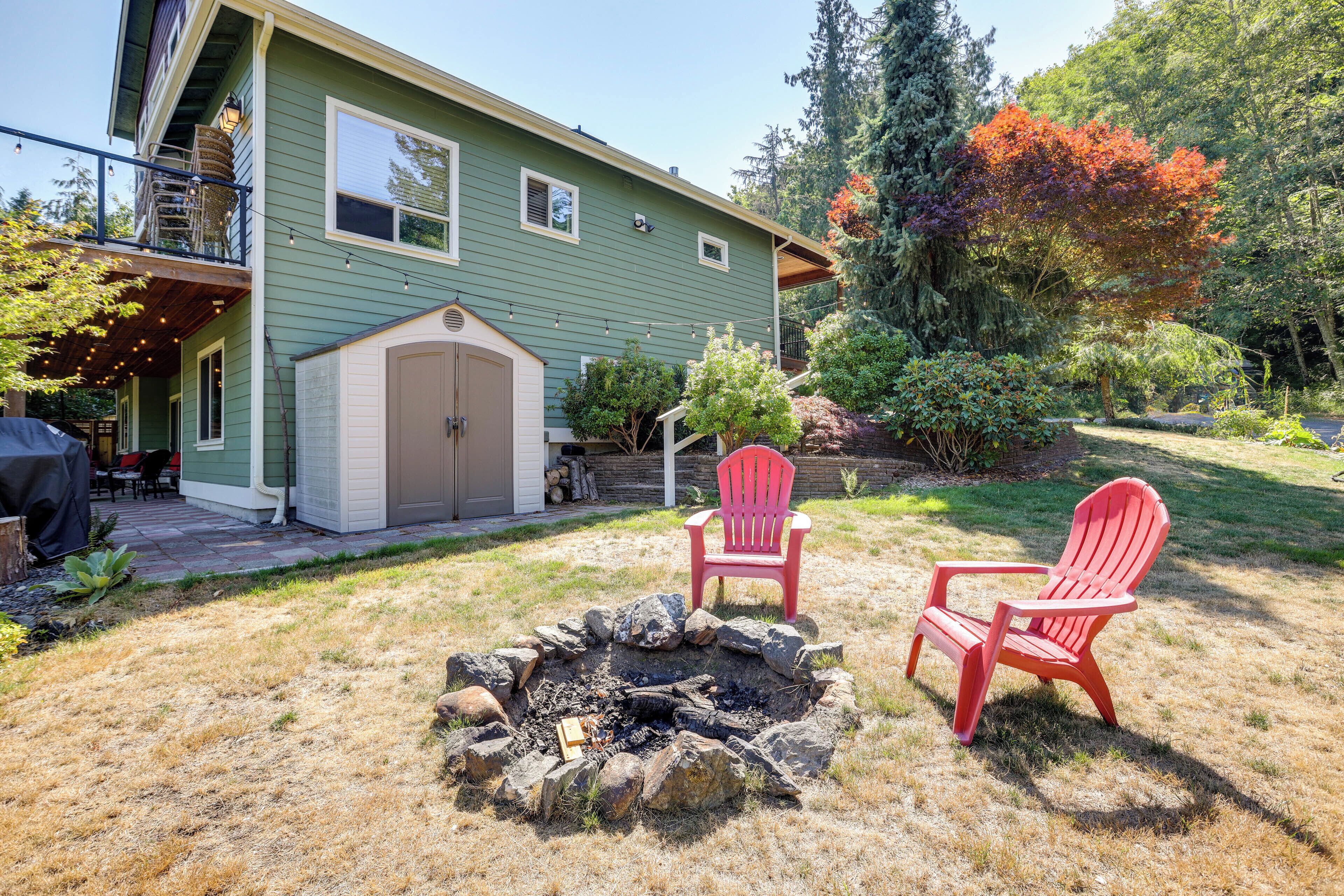 Ein Haus mit Feuerstelle und zwei roten Adirondack-Stühlen im Garten.