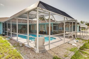 A covered swimming pool with a glass enclosure, a patio area, and a small deck.