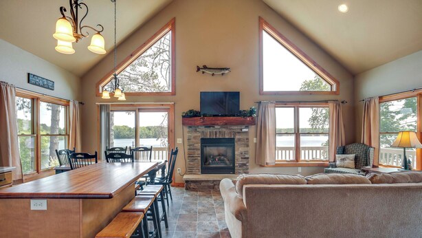 Un amplio salón con chimenea, ventanas grandes, una barra de madera y una zona de estar confortable.