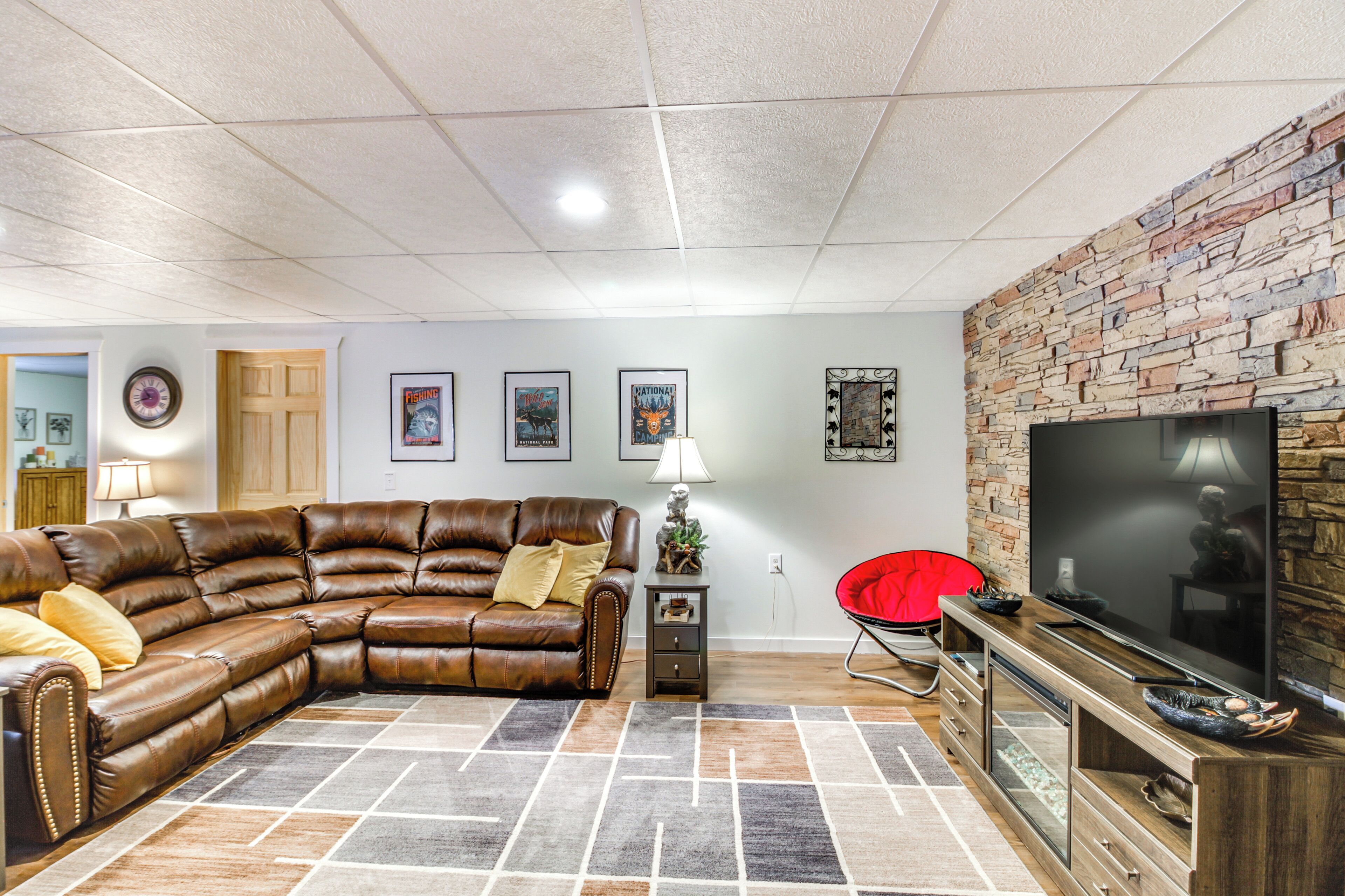 A living room with a sectional sofa, a flat-screen TV, and a stone accent wall.