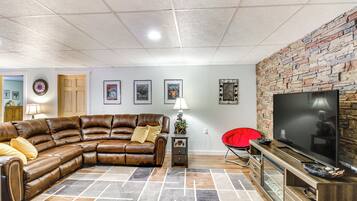 A living room with a sectional sofa, a flat-screen TV, and a stone accent wall.