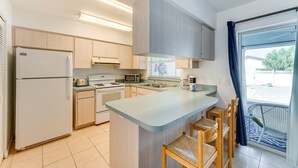 A modern kitchen with a central island, built-in appliances, and a view to the outside.