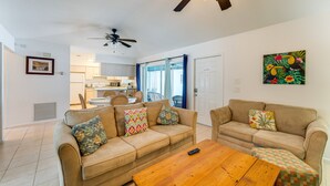 A living room with two beige sofas, a wooden coffee table, and a ceiling fan.