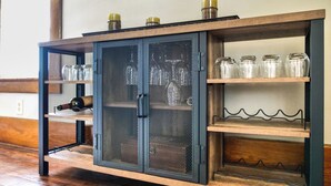 Un meuble en bois doté de portes et d’étagères en treillis métallique, contenant des bocaux et des bouteilles en verre.