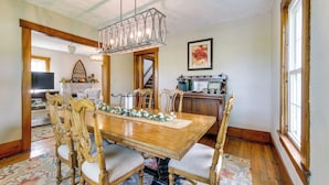Une salle à manger avec une table en bois, des chaises et un lustre.