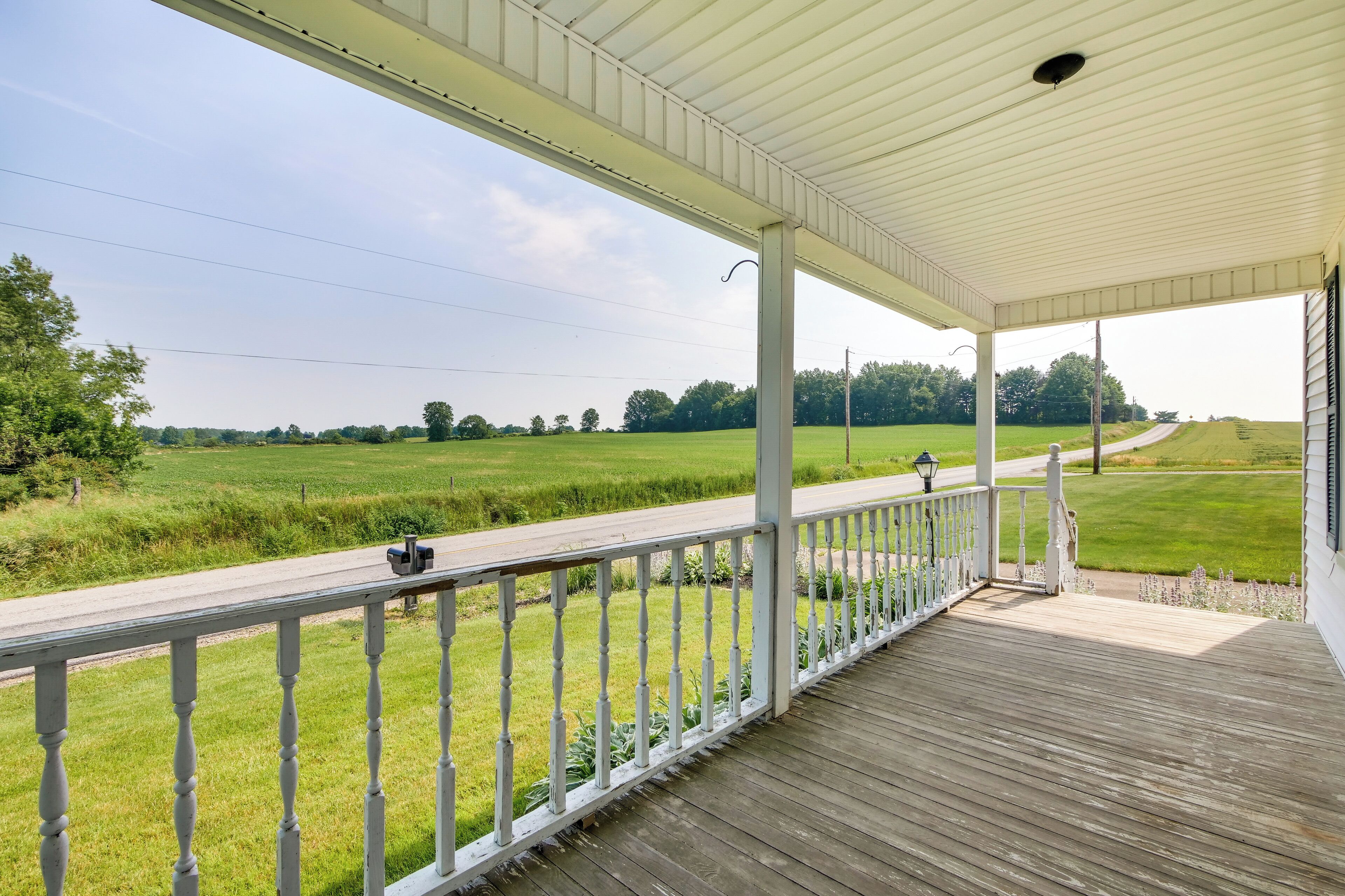 A covered porch with a view of a rural landscape.