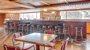 A restaurant with a checkered floor, wooden ceiling, and bar area with stools.