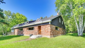 A two-story stone house with a gabled roof, a front porch, and a well-maintained lawn.