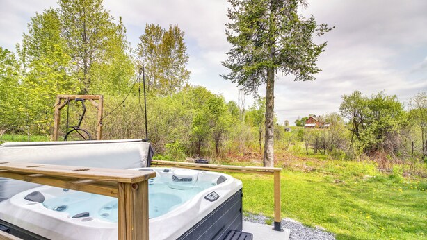 A hot tub on a wooden deck with a view of a grassy area and trees. - Vermont Vacation Rental: Hot Tub, Near Ski Resorts (Mount Holly)