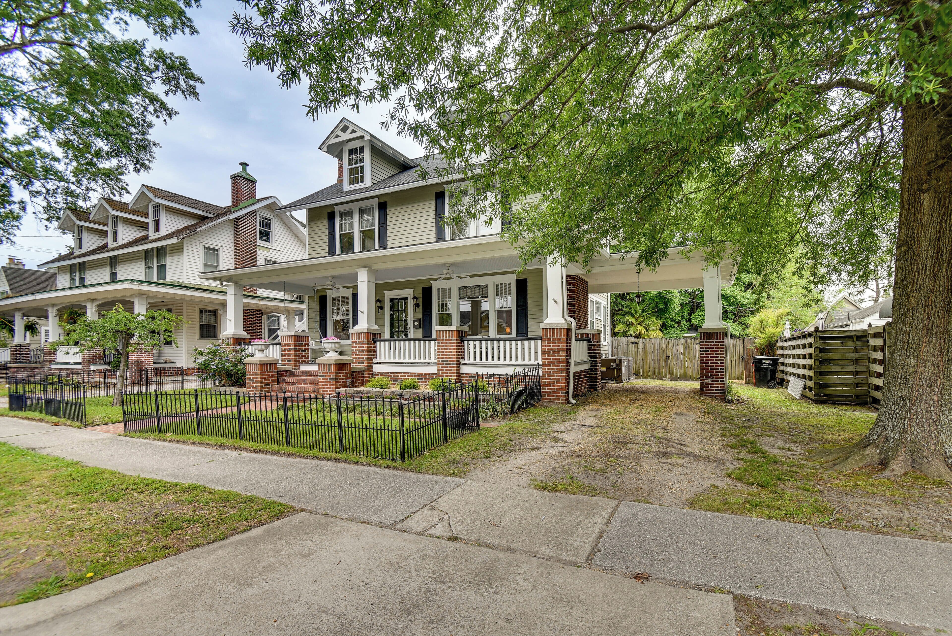 A two-story house with a front porch, brick chimney, and a fenced yard.